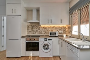 A compact kitchen with white cabinetry, a built-in oven, a washing machine, a microwave, and a sink. - Apartment 'Casa Con Vistas 2' with Mountain View, Wi-Fi and Air Conditioning (FRIGILIANA)