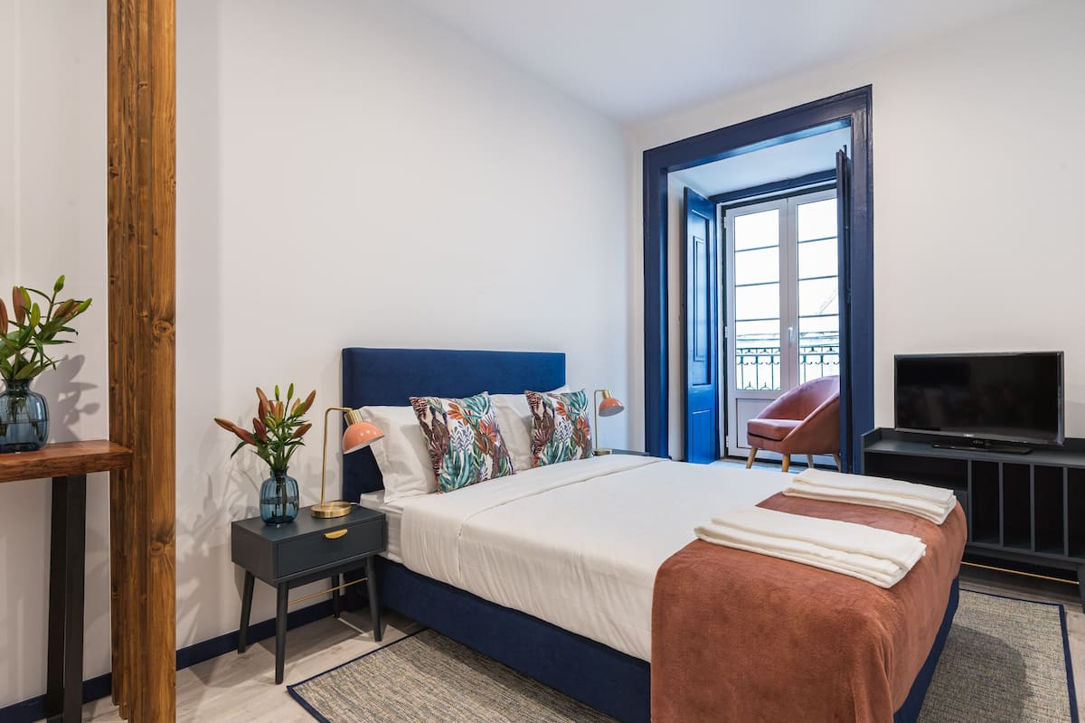 Een hotelkamer met een bed, nachtkastjes, een televisie en uitzicht.