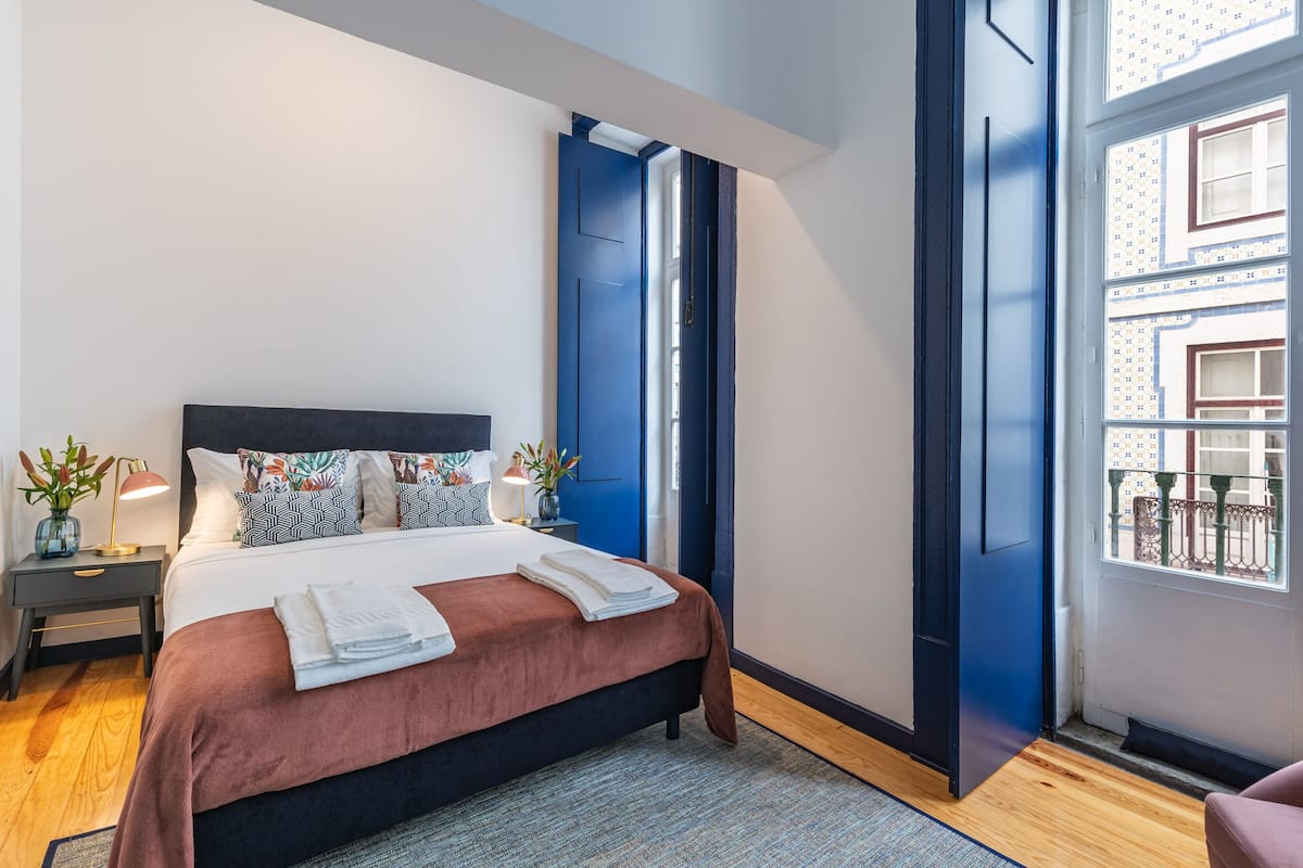Een moderne slaapkamer met een groot bed, nachtkastjes en uitzicht op het balkon.