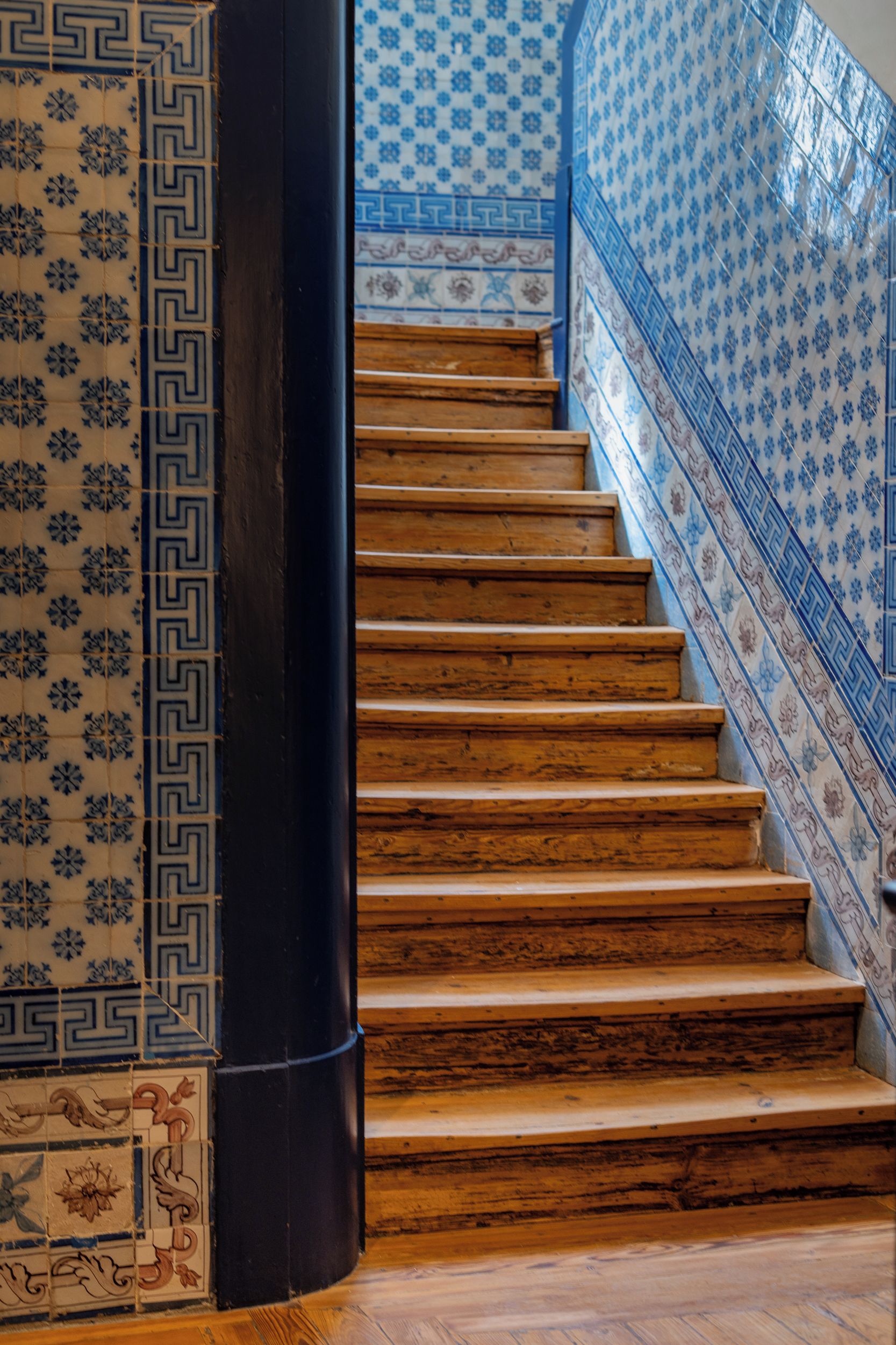 Escada com degraus de madeira e paredes com padrão azul.