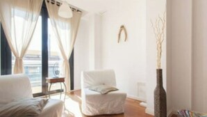Ein modernes Wohnzimmer mit einem weißen Sofa, einem weißen Sessel und einer hohen Vase.