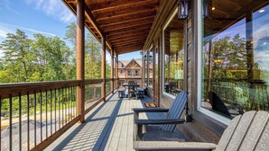 Una terraza de madera con mobiliario exterior, vista a una casa y barandilla.