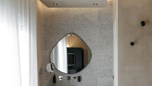 Un baño moderno con un espejo grande, un lavabo redondo y una pileta de madera.
