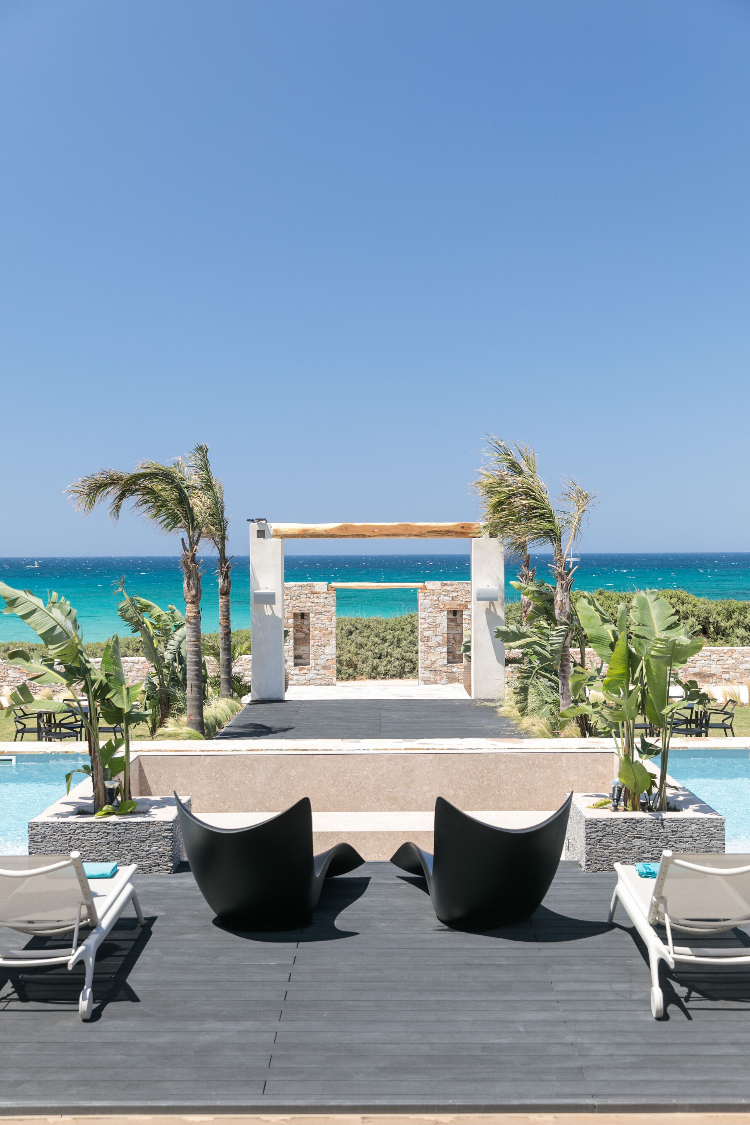 A poolside area with lounge chairs and a view of the ocean.