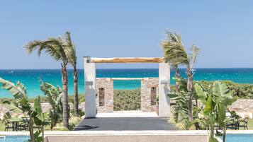A poolside area with lounge chairs and a view of the ocean.