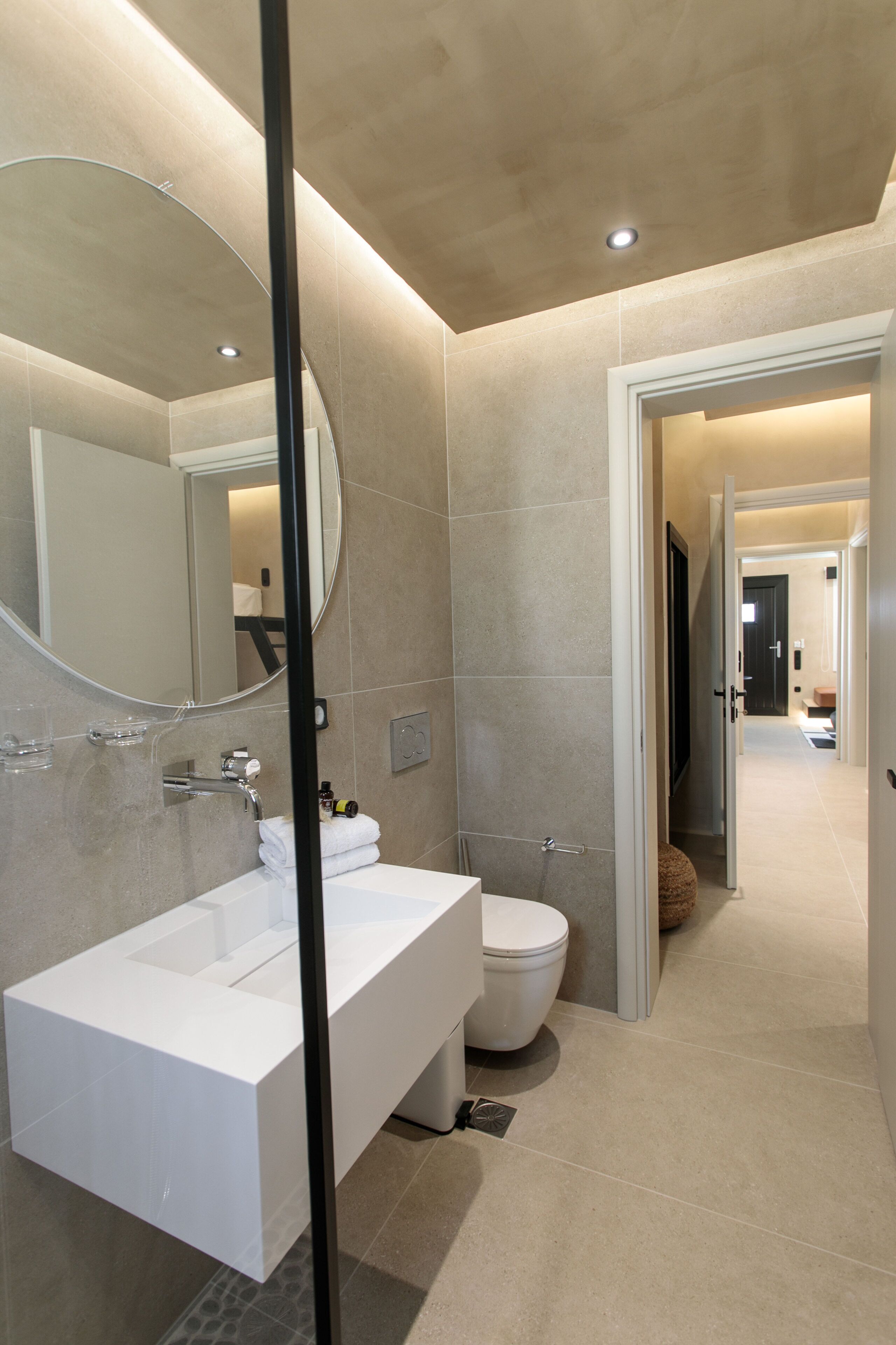 A modern bathroom with a large mirror, a white sink, and a toilet.