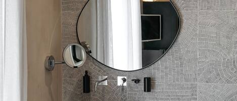 A bathroom with a round mirror, wooden basin, and a patterned wall.
