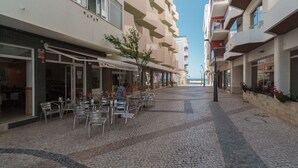 Un vialetto lastricato con posti a sedere all'aperto, un albero e un edificio con diversi balconi e un negozio.
