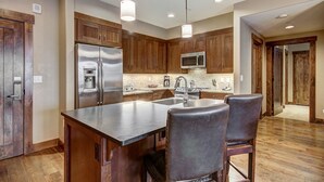 A spacious kitchen with wooden cabinets, stainless steel appliances, and a large island with bar stools. - Centrally located ski chalet with shared hot tub and pool - right in downtown (Breckenridge)