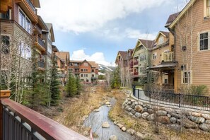 Una zona residencial con edificios de varios pisos, un arroyo y montañas al fondo.