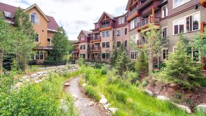A residential area with multiple two-story houses, a small stream, and surrounding greenery. - Centrally located ski chalet with shared hot tub and pool - right in downtown (Breckenridge)