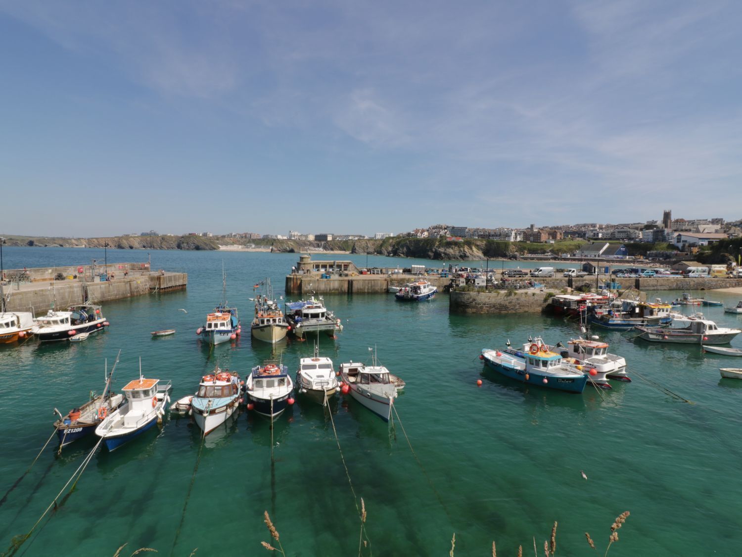 Un puerto con varios barcos amarrados en muelles, rodeado por una ciudad costera.