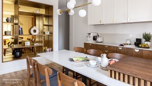 Eine moderne Küche mit weißen Schränken, einem Holztisch und einer Pendelleuchte.