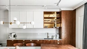 Eine moderne Küche mit weißen Schränken, Holzelementen und einem eingebauten Weinkühlschrank.