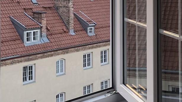Blick aus einem Fenster auf ein Gebäude mit Kuppel und roten Ziegeldächern.