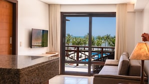 A hotel room with a large window, a flat-screen TV, a sofa, a lamp, and a view of a pool and palm trees. - Kariri 319A (Caucaia)