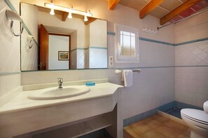 Een badkamer met een wastafel, spiegel en toilet.