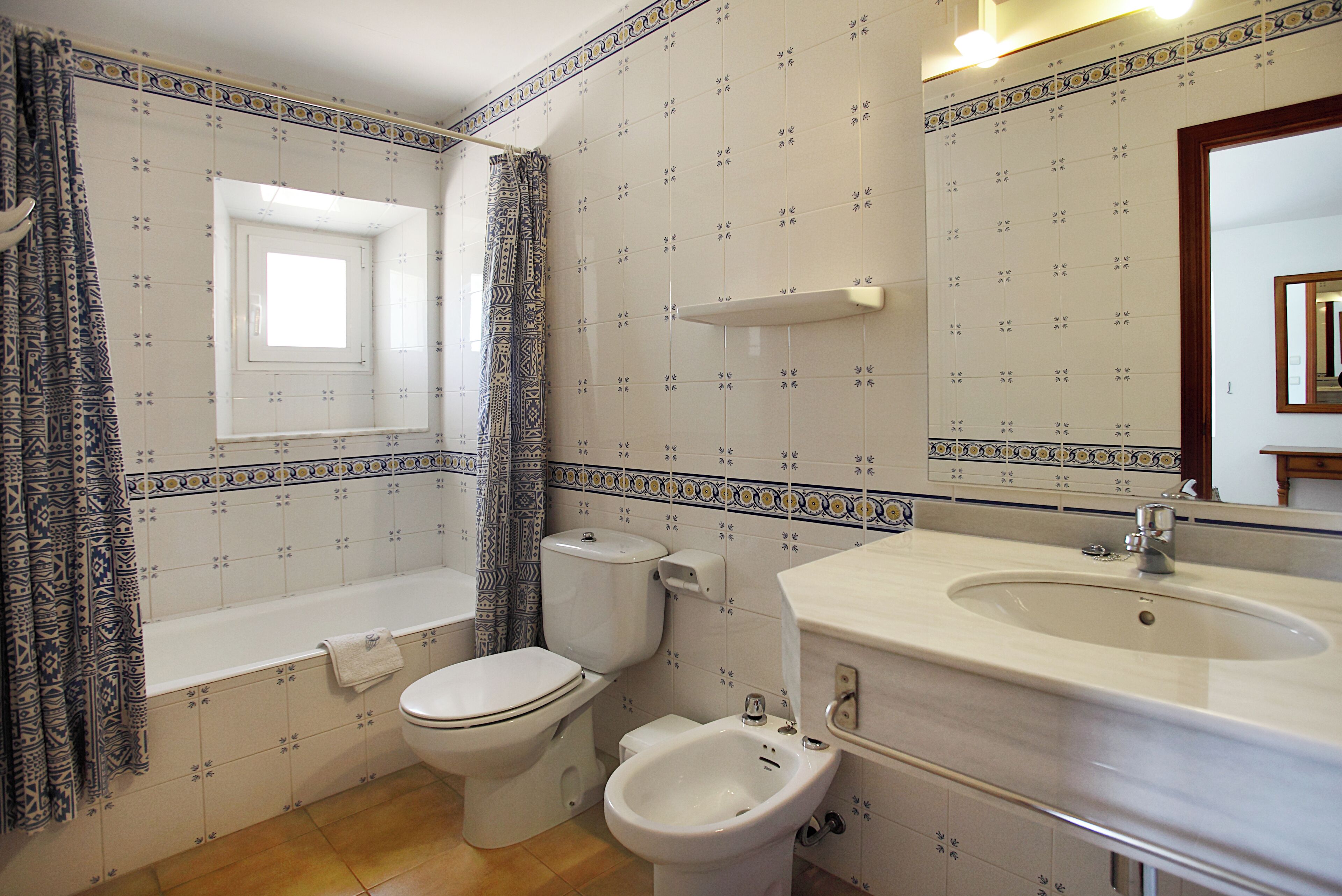 A bathroom with a toilet, bidet, bathtub, and sink.