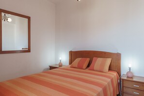 Ein Schlafzimmer mit einem Bett, zwei Nachttischen, einem Spiegel und einer wandmontierten Lampe.
