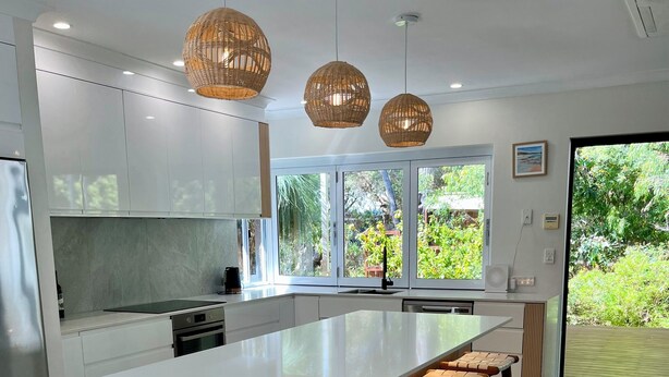 A modern kitchen with a large island, bar stools, and pendant lighting.