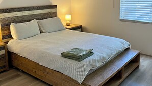 A bedroom with a wooden bed, a ceiling fan, a bedside lamp, and a window with blinds.