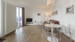 Una sala de estar moderna con televisor, sofá y zona de comedor.