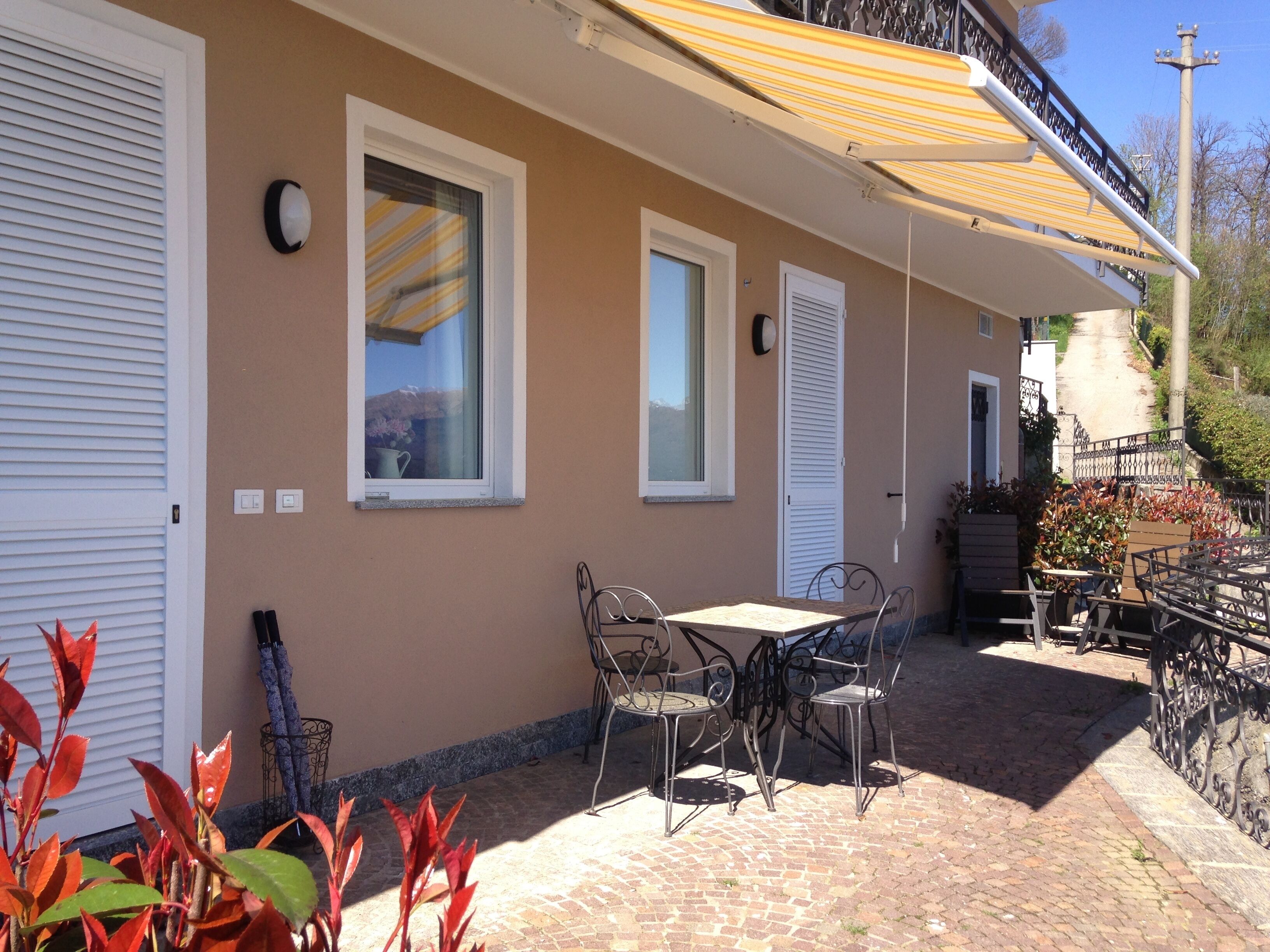 Une terrasse avec une table et des chaises, une fenêtre et une porte.