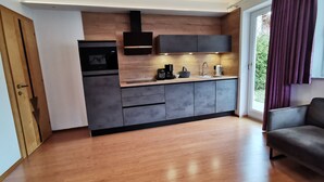 Eine moderne Küche mit grauen Schränken, einer Holzausziehtafel und einem eingebauten Backofen.