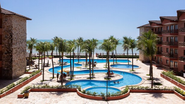 Ein Resort mit mehreren Schwimmbecken, Palmen und Blick auf den Ozean.
