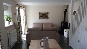 A cozy living room with a sofa, a wooden coffee table, and a fireplace. - Peaceful Rural Retreat, Ideal Base To Explore Cornwall (Wadebridge)