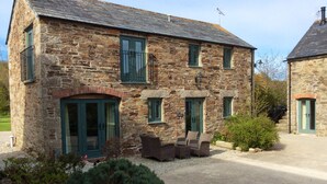 A stone building with a gravel driveway, a small patio with outdoor furniture, and a well-maintained garden. - Peaceful Rural Retreat, Ideal Base To Explore Cornwall (Wadebridge)