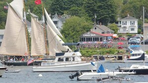 Un port de plaisance avec des voiliers, un restaurant situé au bord du quai et des maisons en arrière-plan.