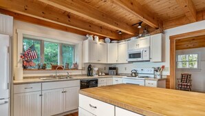 Une cuisine avec des armoires blanches, un plan de travail en bois et une fenêtre décorée de drapeaux américains.