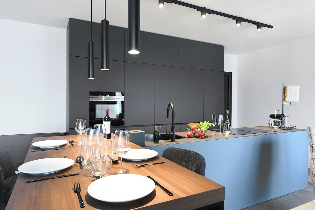A modern kitchen with a central island, dark cabinetry, and pendant lighting.