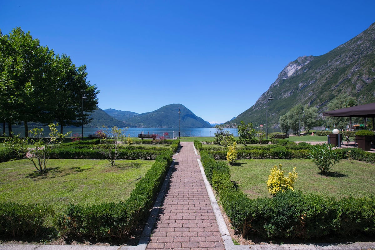 A paved pathway leading to a lake with mountains in the background.
