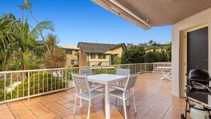 Enjoy al fresco dining on the balcony with a grill and seating for two, overlooking the surrounding neighborhood and lush greenery.