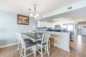 A modern kitchen with white cabinets, a central island, and a dining area with a table and chairs.