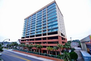 A multi-story hotel with a central courtyard, balconies, and a parking garage.