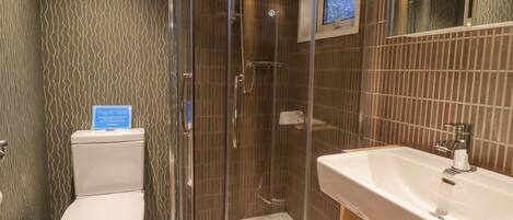 A bathroom with a glass-enclosed shower, a toilet, and a sink.