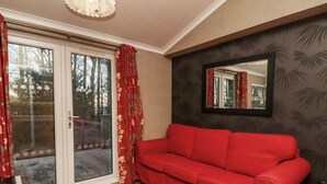 Habitació amb un sofà vermell, una porta de vidre que dona a l'exterior, una catifa amb dibuixos i un mirall a la paret.