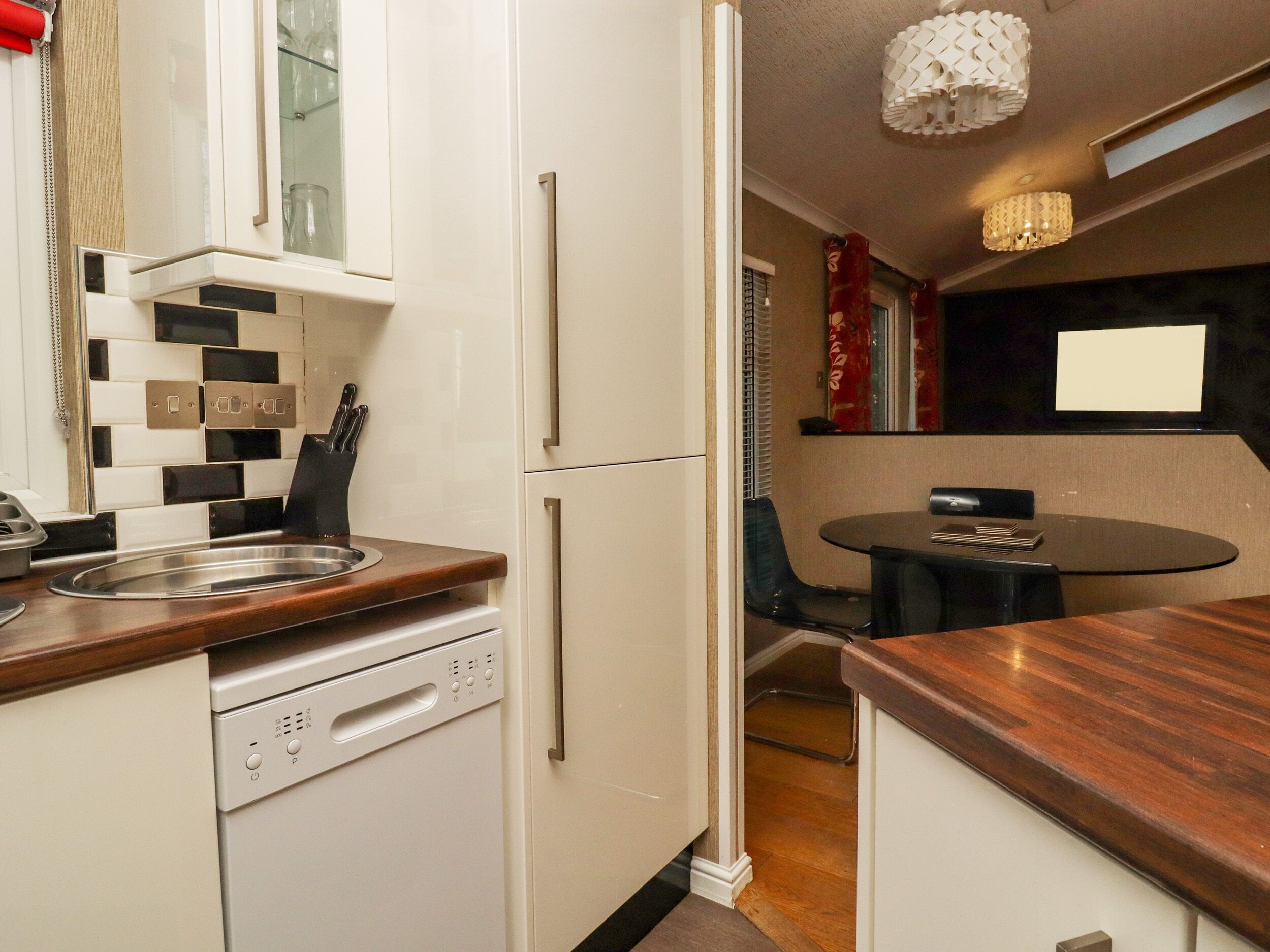 A compact kitchen with a dishwasher, a sink, and a dining area with a table and chairs.