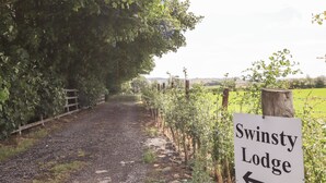 Camí de grava que condueix a Swintry Lodge amb un senyal que indica la direcció.
