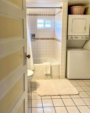 A bathroom with a toilet, bathtub, and a washing machine. - Bluebird Day - Desert Moon, Cozy 2BR in Bend's River West, Walkable to restaurants! (Bend)