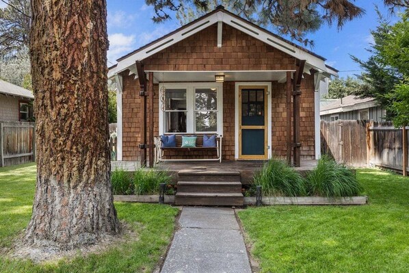 A small, single-story house with a porch, a front door, and a visible staircase leading to the entrance. - Bluebird Day - Desert Moon, Cozy 2BR in Bend's River West, Walkable to restaurants! (Bend)