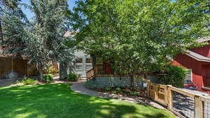 A residential property with a well-maintained lawn, a wooden fence, and a red building. - Bluebird Day - Hartford Haven, a spacious 3BR home with modern amenities. (Bend)