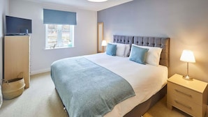 A bedroom with a large bed, bedside tables, a television, and a window with a view. - Host & Stay | Harbour View (Whitby)