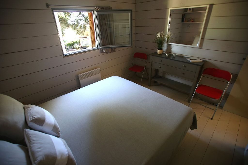 Une chambre à coucher avec un lit, un bureau, une chaise, une commode et une fenêtre.
