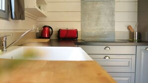Une cuisine équipée d’un évier, d’une bouilloire et d’un sac rouge posé sur le plan de travail.