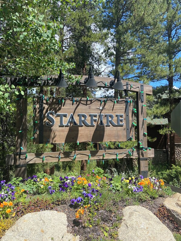Une enseigne en bois portant le nom « Starfire », entourée de fleurs colorées et de verdure.