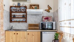 A compact kitchen with a wooden cabinet, a microwave, a toaster, and a small sink. - Cottage Cozy Studio (Yianna Cottage Studios) (Skopelos)
